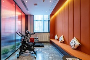 A gym with exercise bikes, a bench, and a window with natural light. - Super 8 Collection Hotel Beijing Guomao Baiziwan Subway Station (Beijing)
