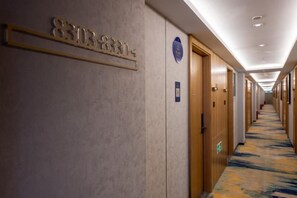 A hotel corridor with doors, a carpeted floor, and a sign with a phone number. - Super 8 Collection Hotel Beijing Guomao Baiziwan Subway Station (Beijing)