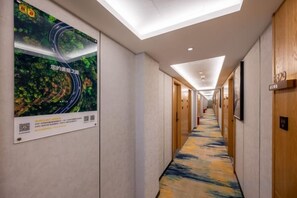 A hotel corridor with a ceiling light, a poster on the wall, and a carpeted floor. - Super 8 Collection Hotel Beijing Guomao Baiziwan Subway Station (Beijing)