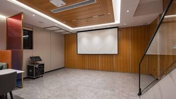 A conference room with a projector screen, a laptop, and a presentation podium.