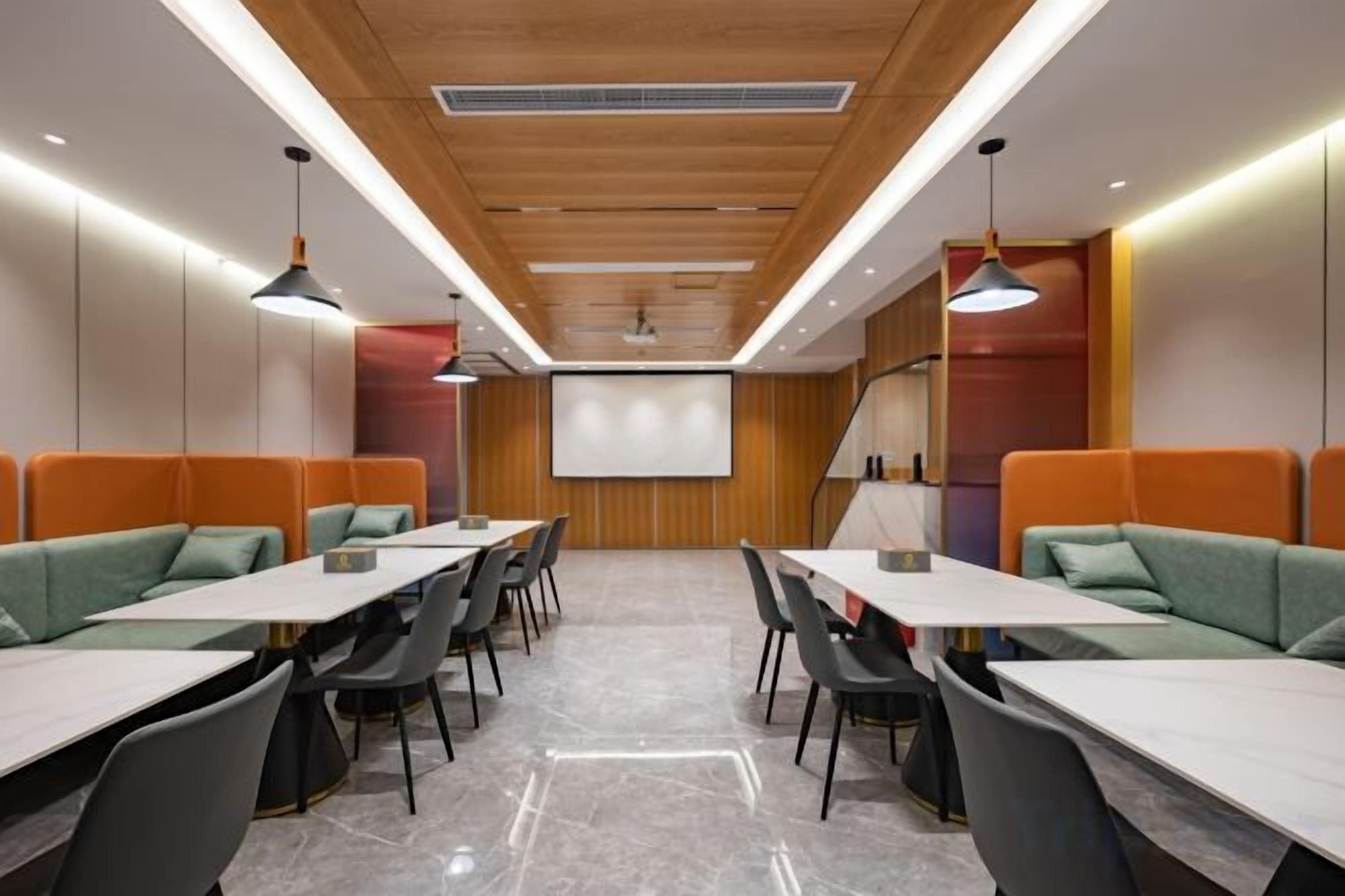 A conference room with a long table, multiple chairs, and a screen at the front.