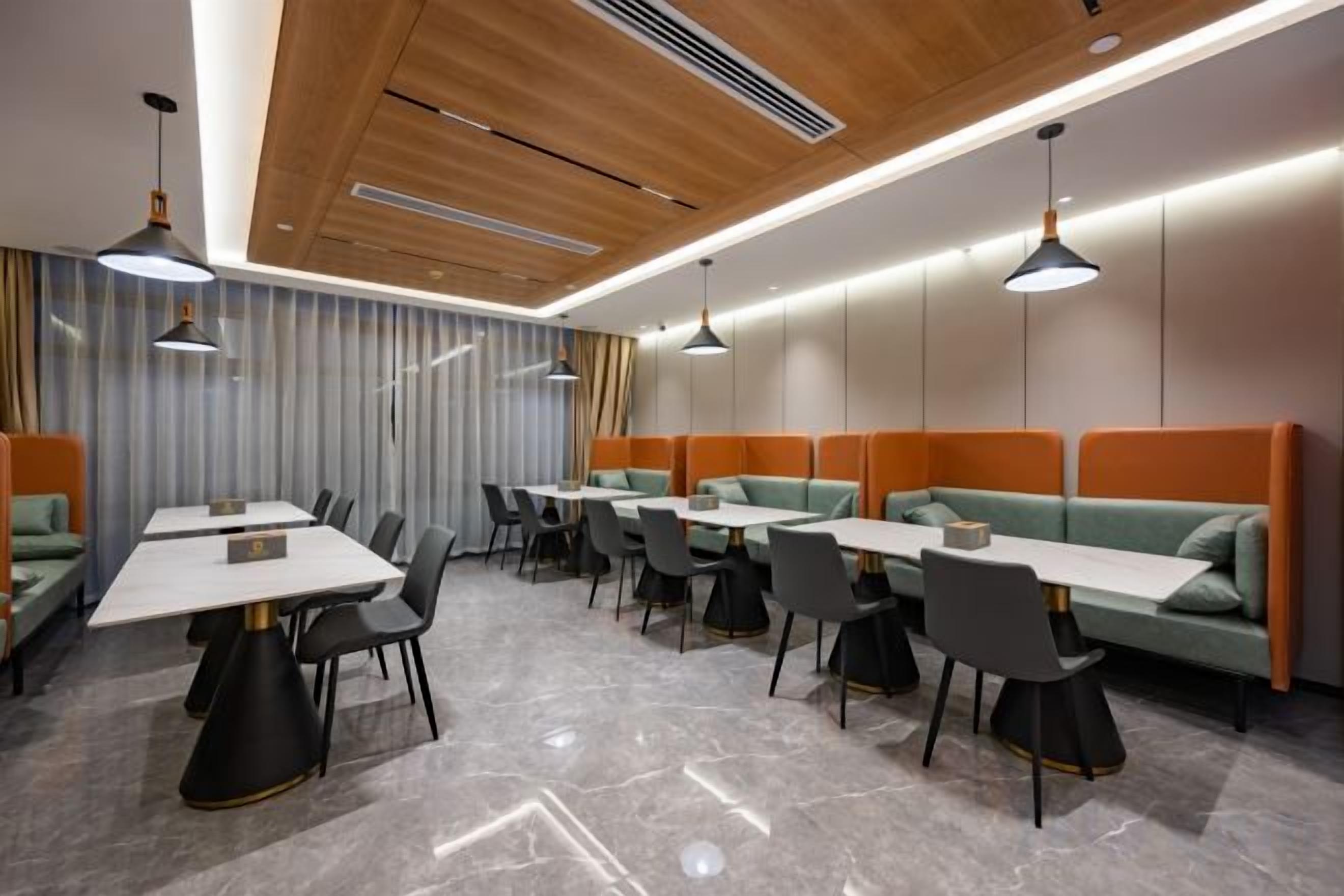 A modern dining area with tables and booths, marble flooring, and pendant lighting.