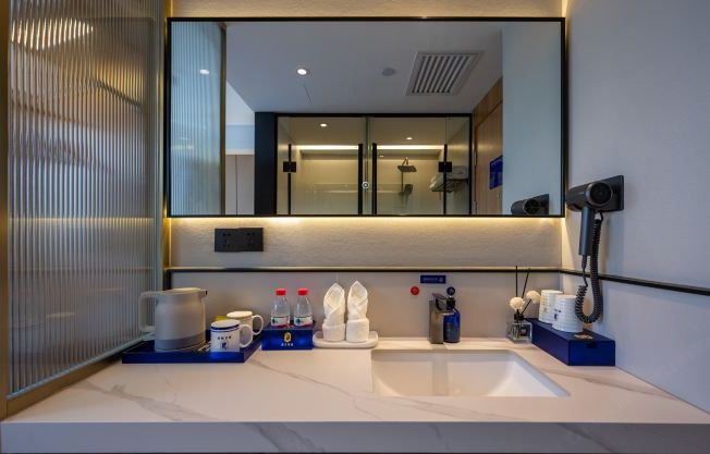 A modern bathroom with a large mirror, a sink, and a shower area.