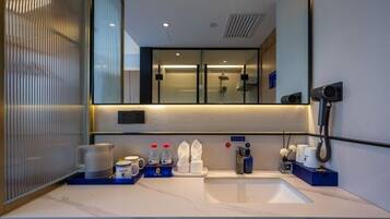 A modern bathroom with a large mirror, a sink, and a shower area.