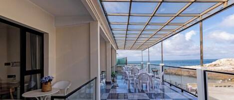 Un balcon doté d’une paroi vitrée, une table avec des chaises et une vue sur la mer.