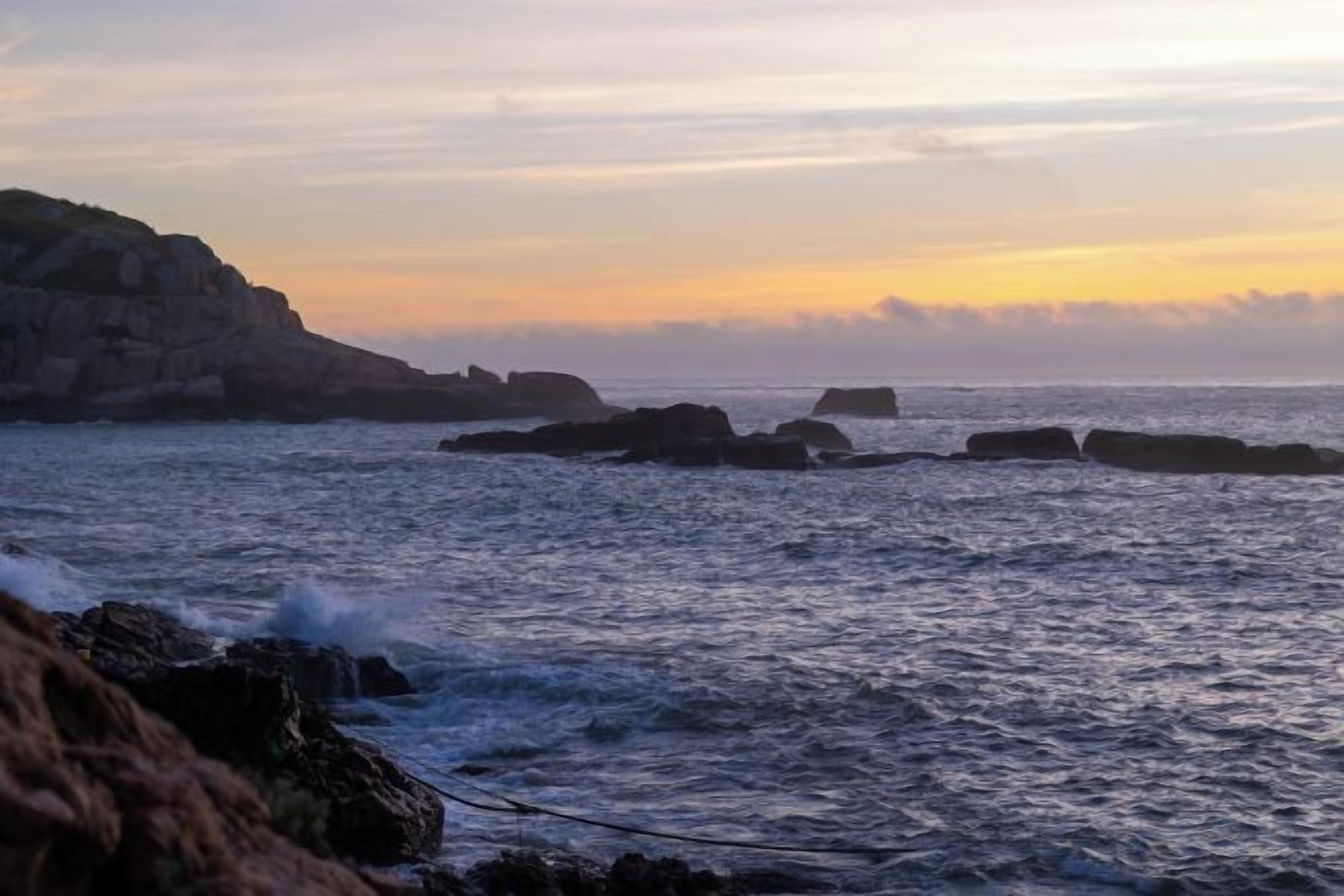 A coastal landscape with rocky formations and calm sea.
