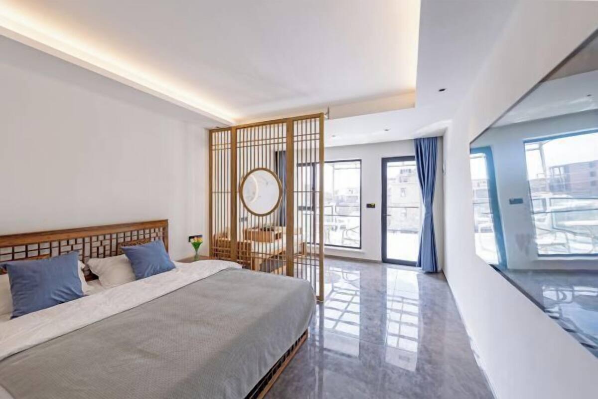 Habitación de hotel moderna con una cama grande, un panel de madera y vistas a la ciudad.