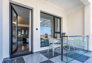 Un balcon doté d’une balustrade en verre, d’une table à manger et de chaises.