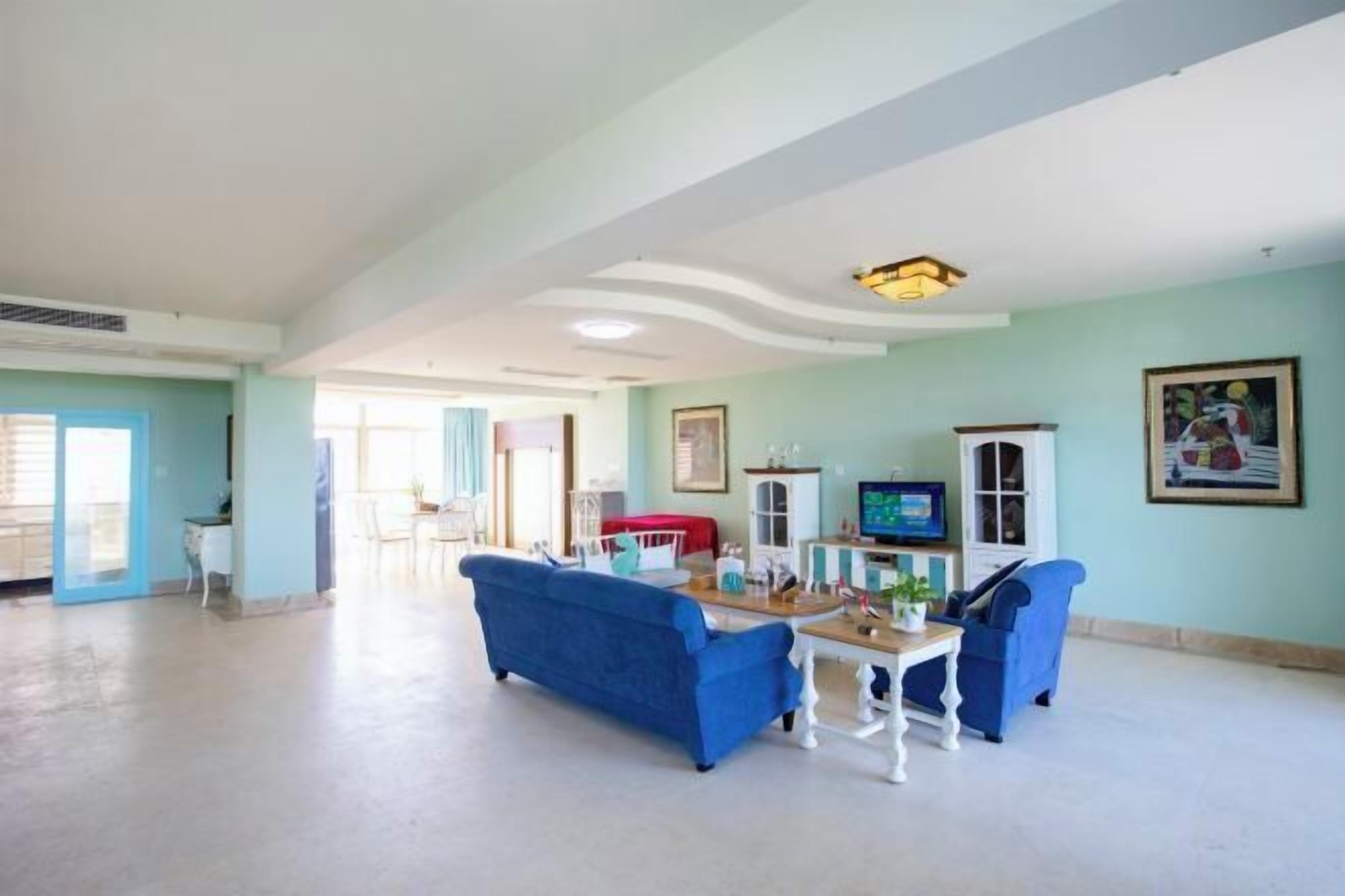A spacious living area with a blue sofa, a small table, and a television.