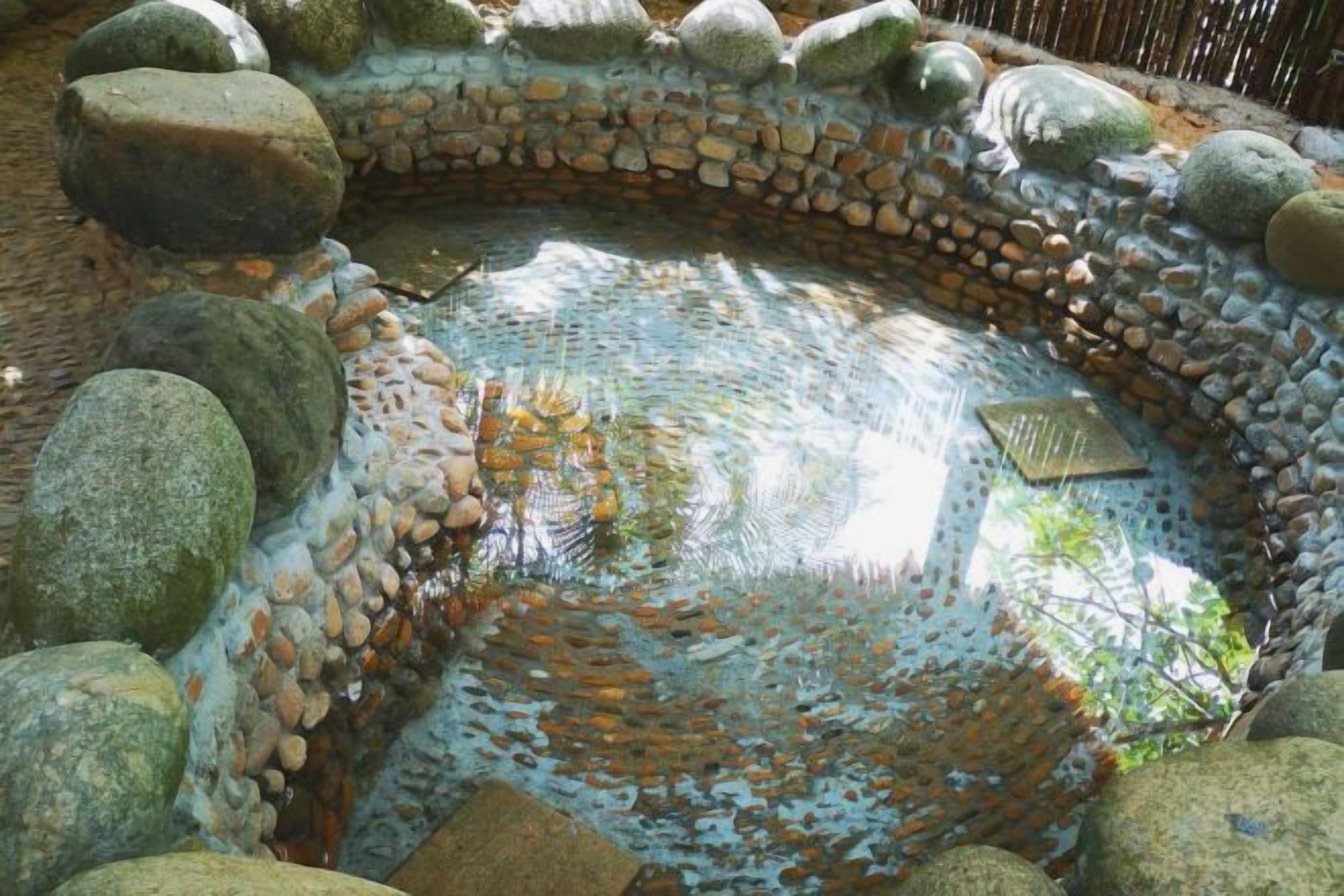 A circular stone water feature surrounded by rocks.