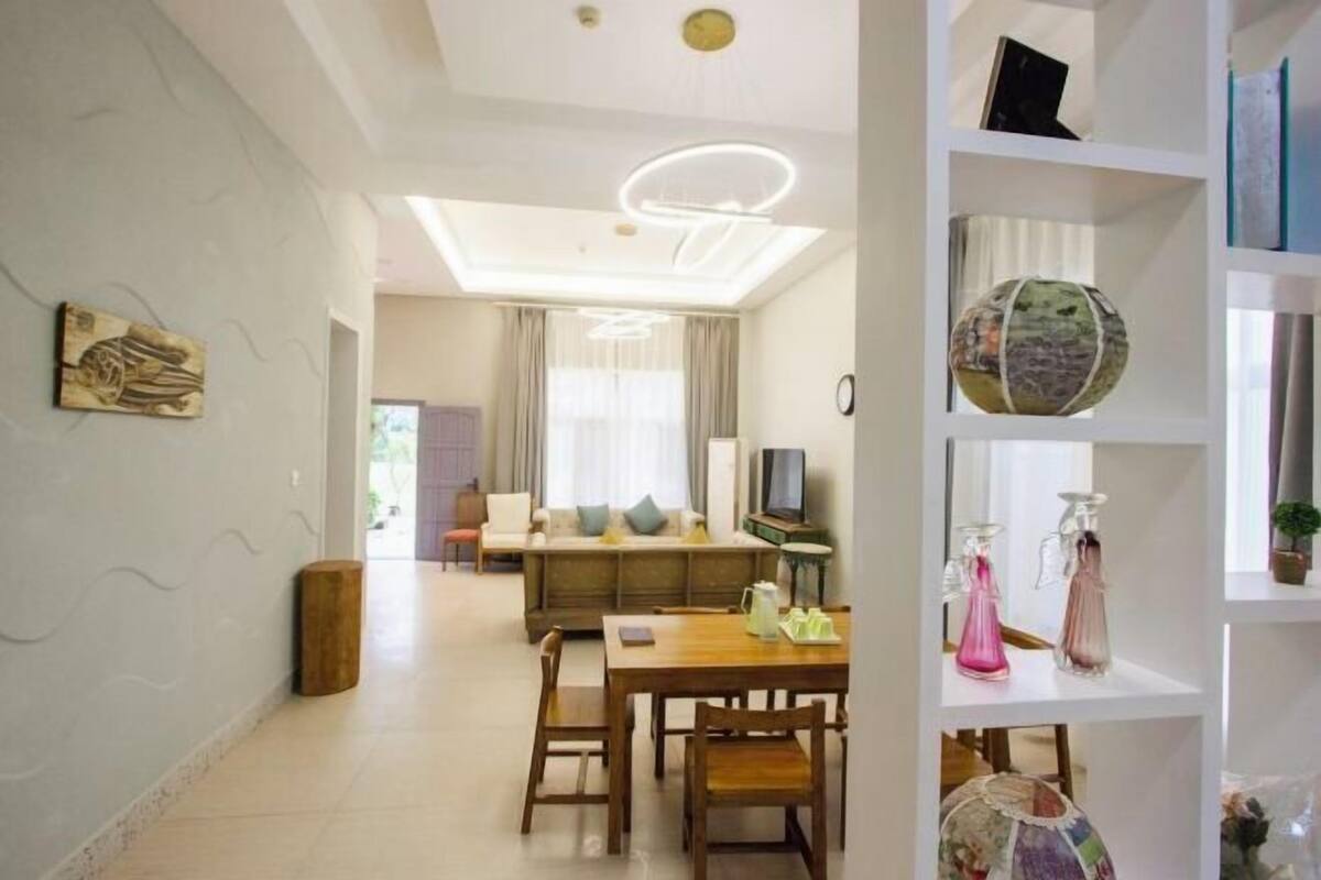 A modern living room with a sofa, TV, and a dining area with chairs and a table.