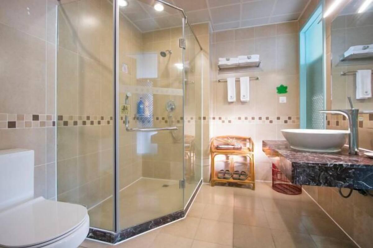 A modern bathroom with a glass-enclosed shower, a toilet, a sink with a large basin, and a vanity with a mirror.