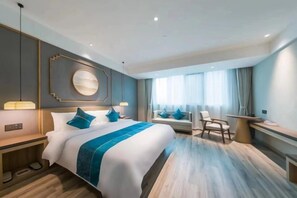 Een moderne hotelkamer met een groot bed, nachtkastjes, een bureau en een zithoek.