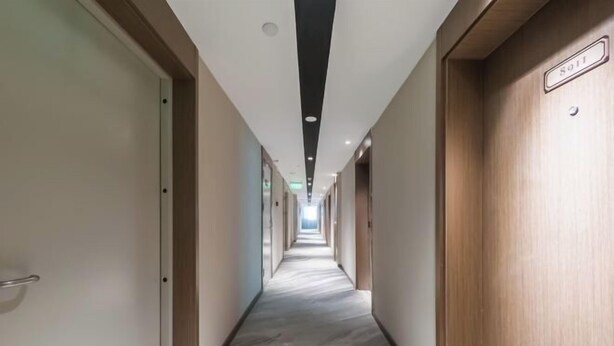 Ein Hotelkorridor mit Marmorboden, Holztüren und einer Decke mit eingelassener Beleuchtung.