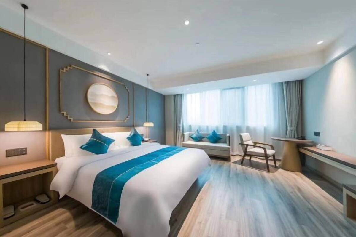 Een moderne hotelkamer met een groot bed, nachtkastjes, een bureau en een raam met gordijnen.