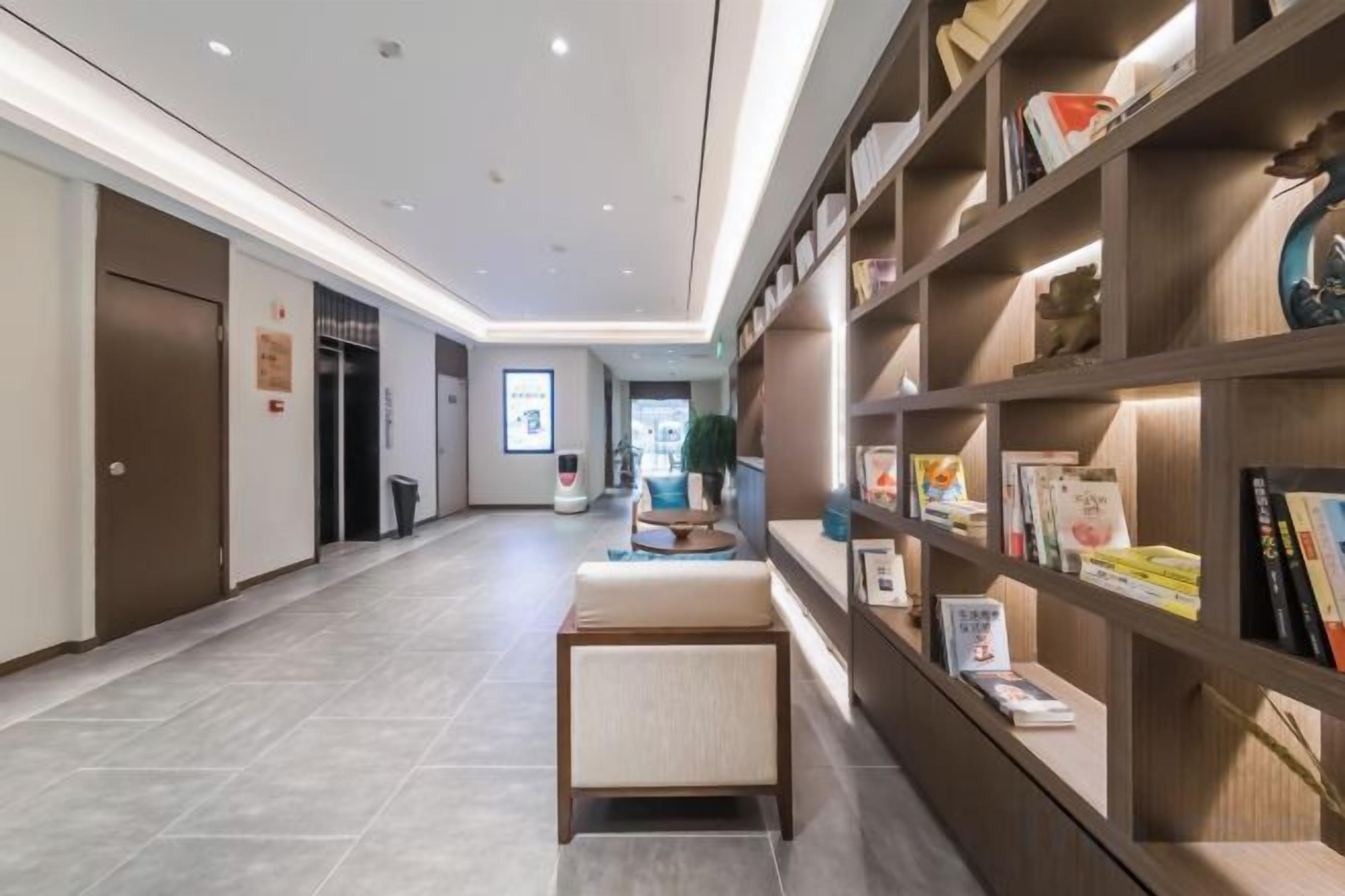 A hallway with a bookshelf, a bench, and a door.