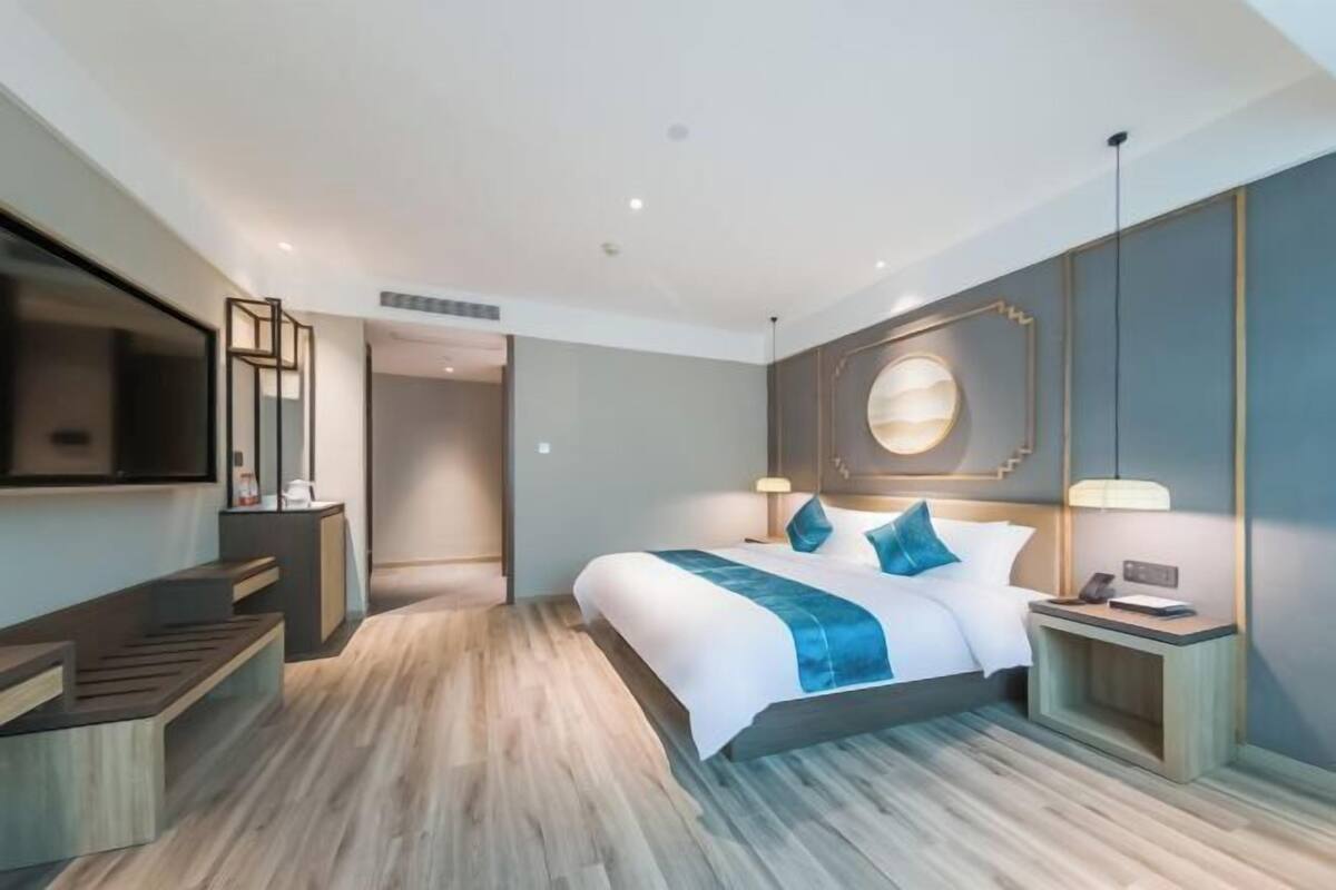 Een moderne hotelkamer met een groot bed, nachtkastjes, een flatscreen-tv en een wandlamp.
