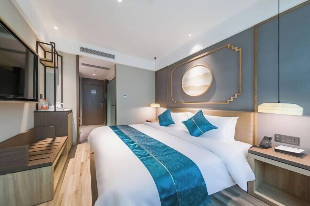 Een hotelkamer met een groot bed, nachtkastjes, een televisie en een wandlamp.