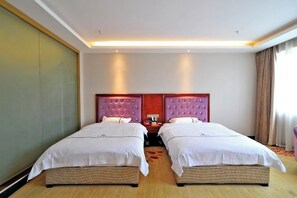 A hotel room with two single beds, a wooden floor, a large mirror, and a red accent wall.