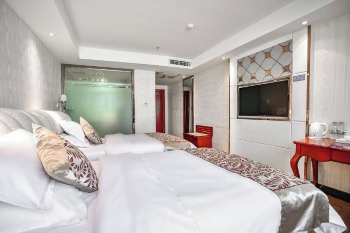 A hotel room with a large bed, a desk, a television, and a mirror.