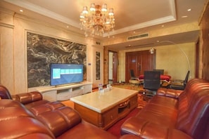A spacious living area with leather sofas, a flat-screen TV, a marble coffee table, and a large abstract painting on the wall. - HAI YUAN HOTEL (Guiyang)