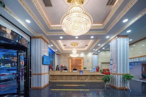 A hotel lobby with a reception desk, a chandelier, and a large window. - Shencheng Hotel (Xuancheng RT Mart Branch) (Xuancheng)