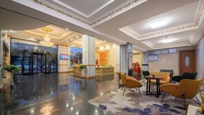 Un vestíbulo de hotel con mostrador de recepción, zona de estar y puerta giratoria.