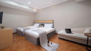 Habitación de hotel con dos camas, un sofá, un escritorio y una computadora portátil.