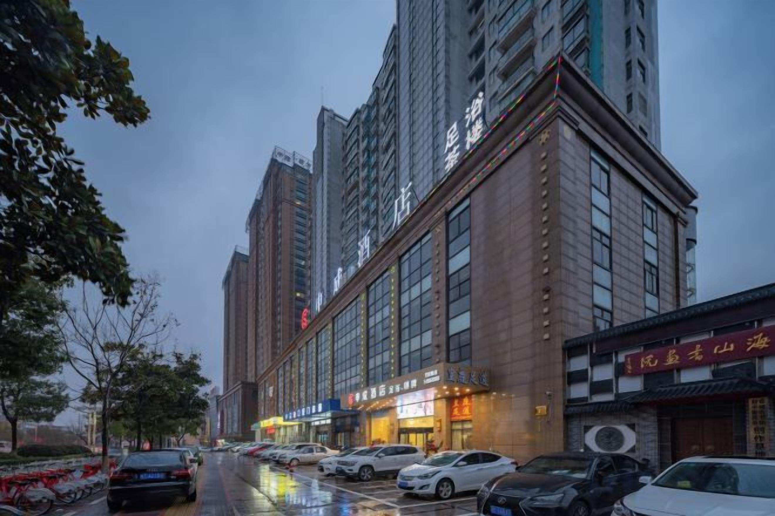 A multi-story building with a row of parked cars on the street.