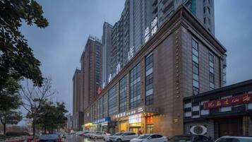 A multi-story building with a row of parked cars on the street.
