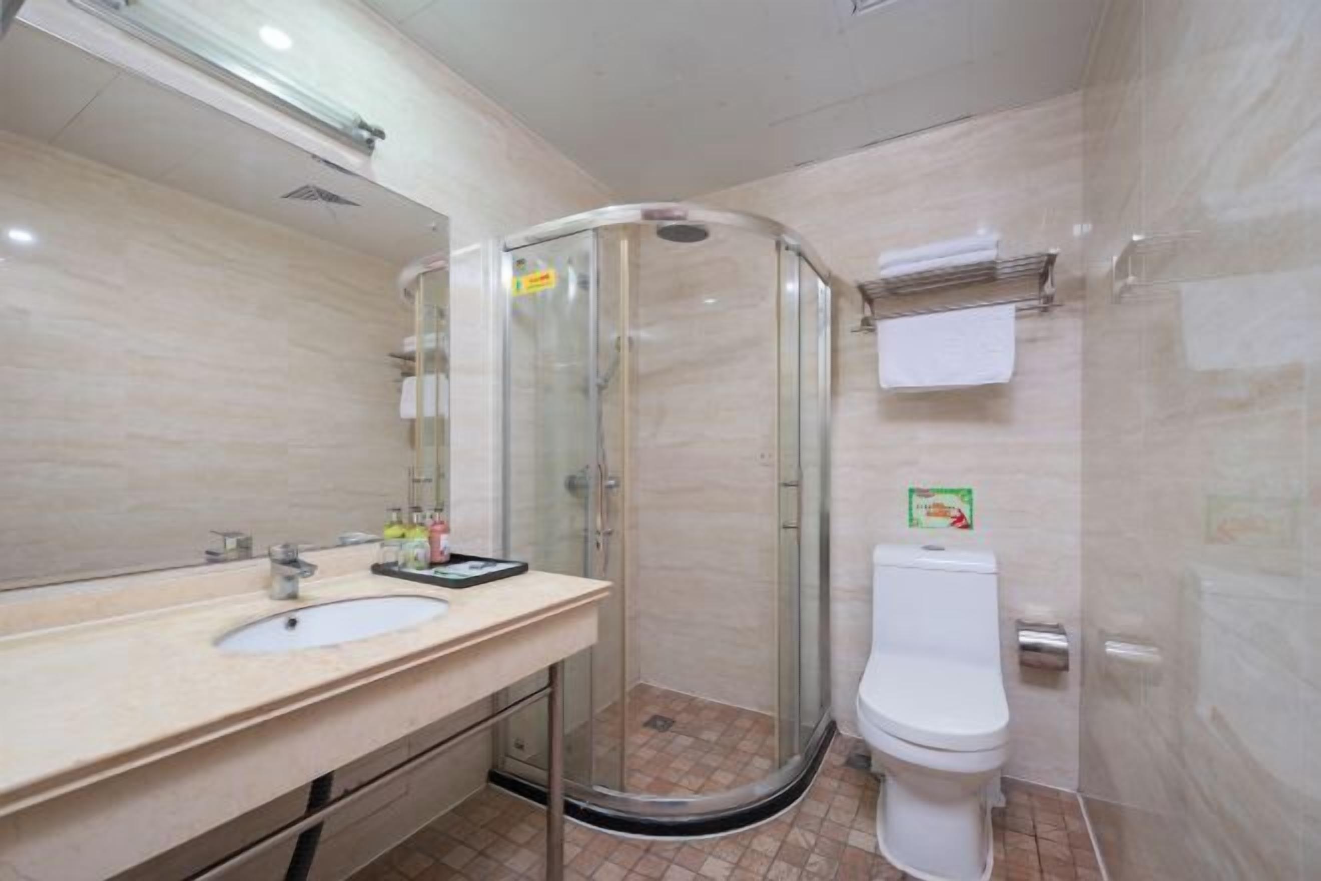 A bathroom with a glass-enclosed shower, a sink with a mirror, and a toilet.