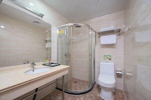 Un baño con ducha envuelta en vidrio, un lavamanos con espejo y un inodoro.