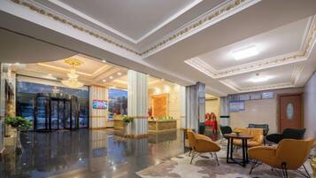 A hotel lobby with a reception desk, seating area, and a glass entrance.