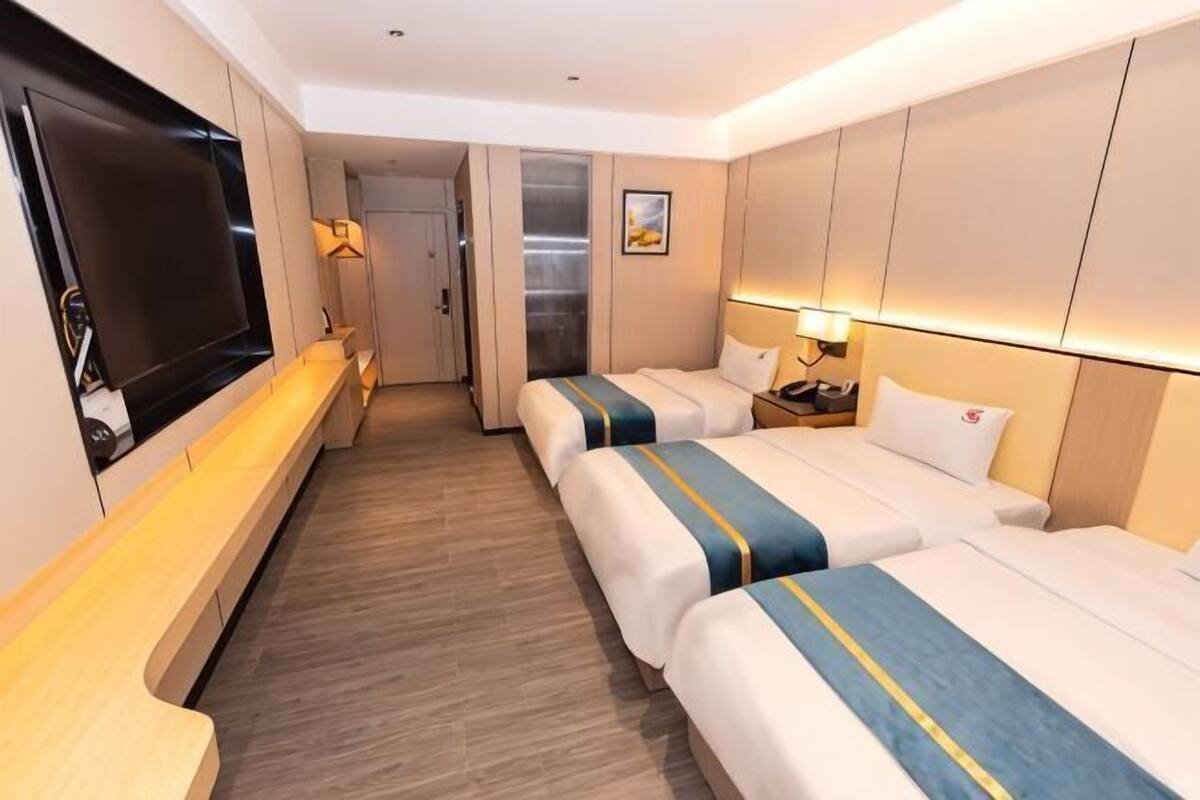 A hotel room with two beds, a TV, a desk, and a door leading to a bathroom.