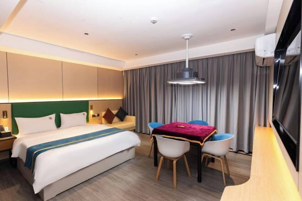 A hotel room with a bed, a desk, a chair, a television, and a curtain.