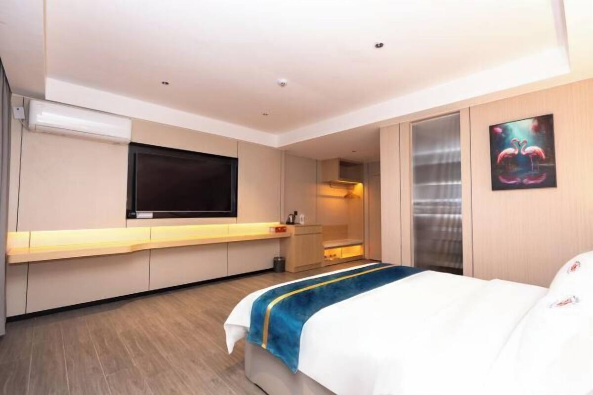 A hotel room with a bed, a TV, a desk, and a bathroom.