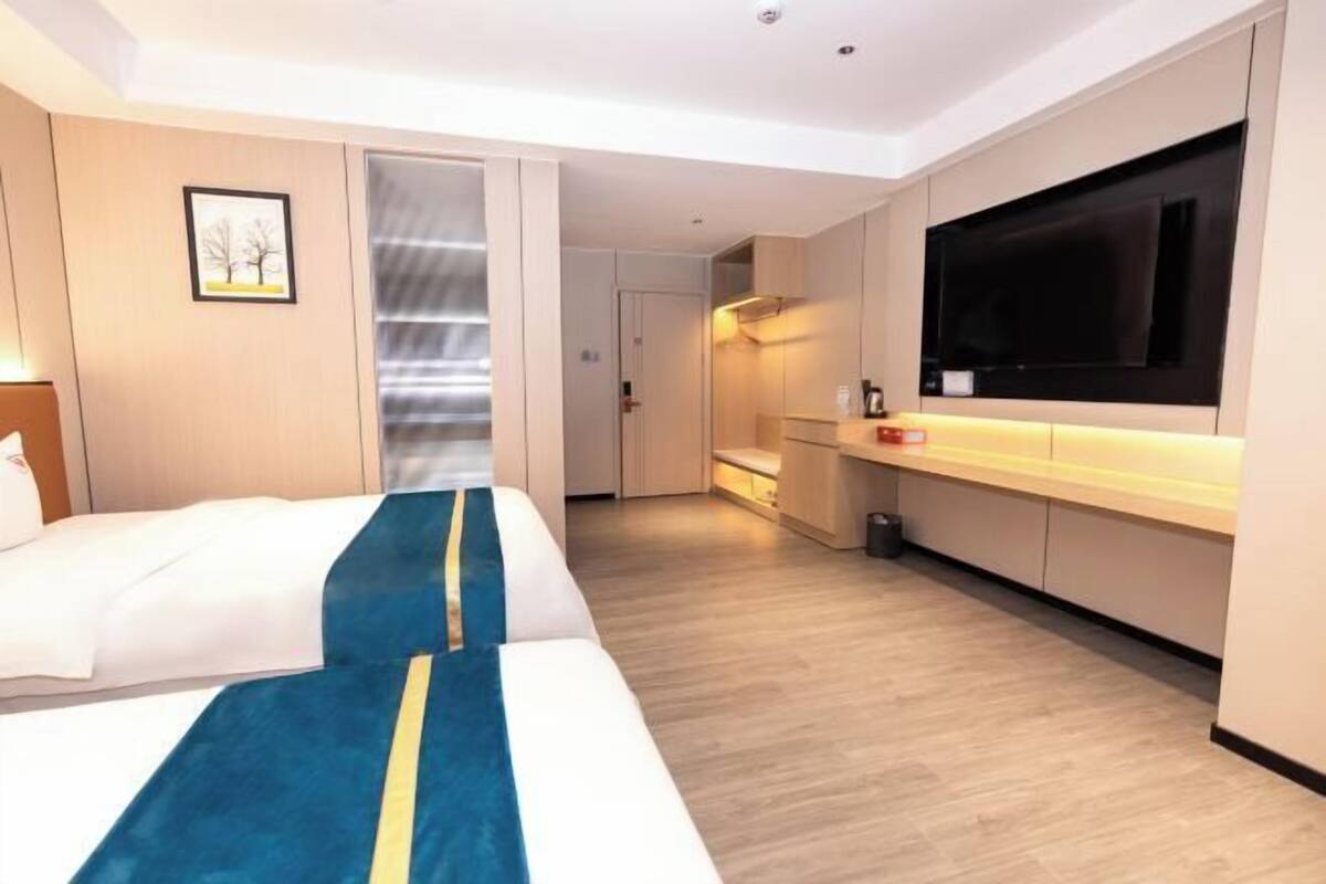 A hotel room with a bed, a TV, a kitchenette, and a sliding door to a bathroom.