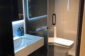 Un bagno moderno con doccia a vetro, lavandino bianco e water.