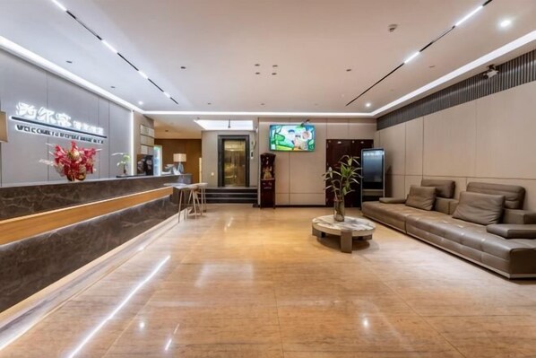 A hotel lobby with a reception desk, seating area, and a television.
