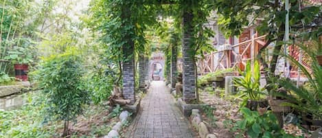 A pathway leading through a garden with a pergola structure.