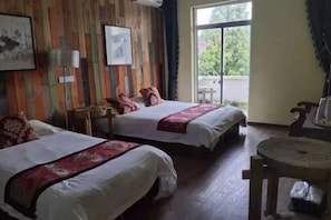 A hotel room with two beds, a wooden wall, a window, and a small round table. - Banduo Youlian Hostel (Shanghai)