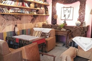 A cozy room with a wooden wall, a bookshelf, a desk, and a sofa. - Banduo Youlian Hostel (Shanghai)