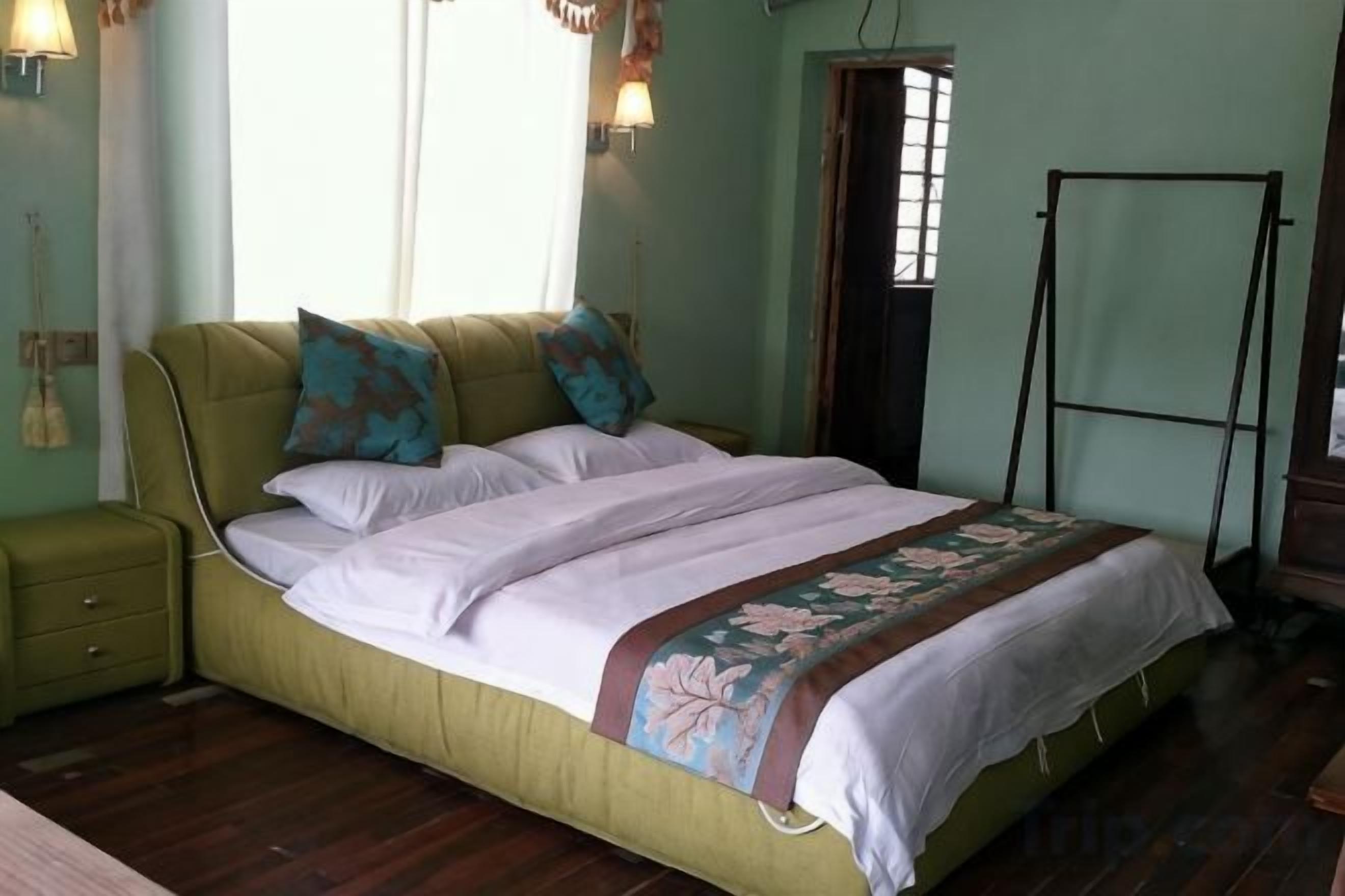 Una cama con cubrecama floral, una mesita de noche y suelo de madera.
