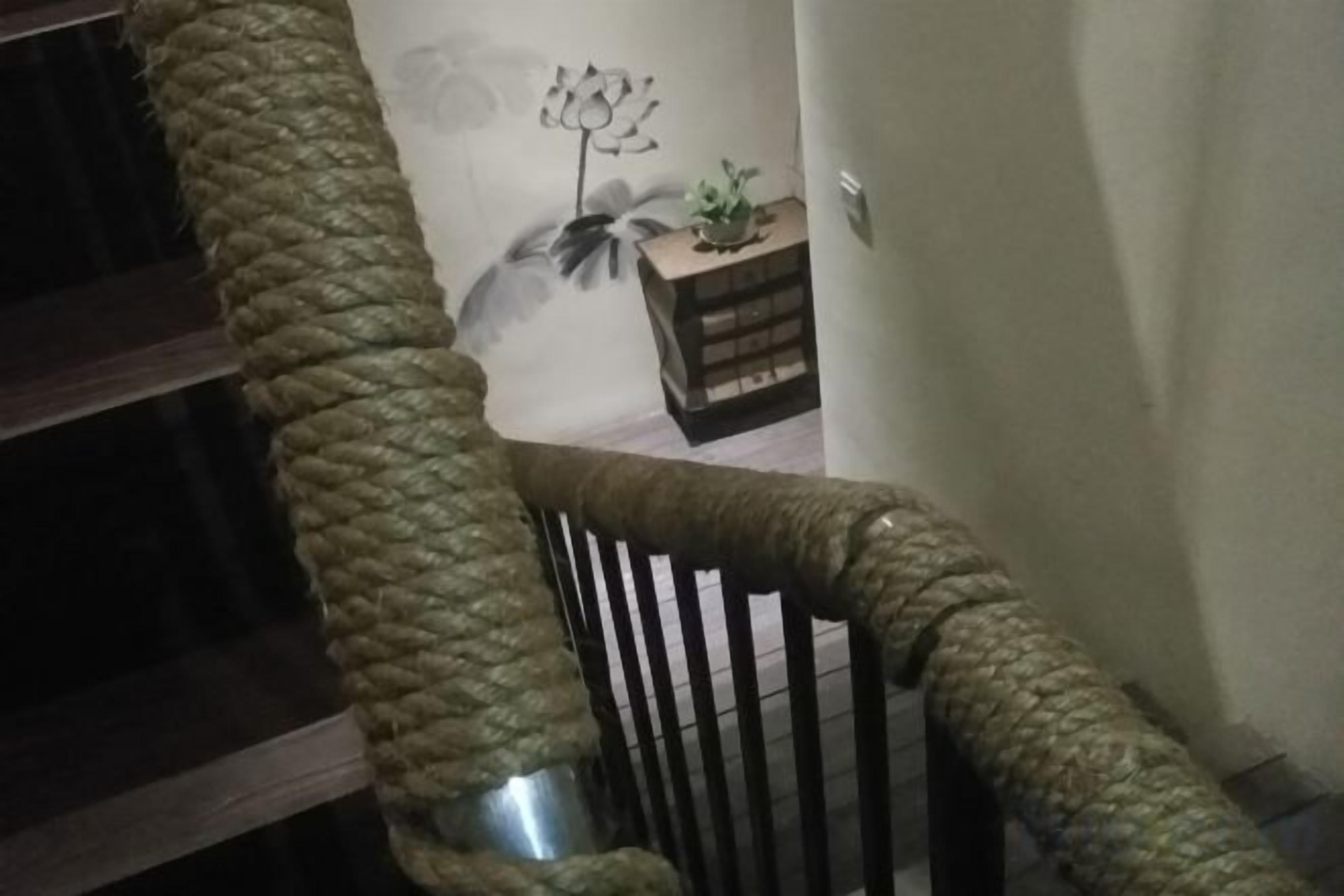A staircase with a rope handrail and a wooden banister.