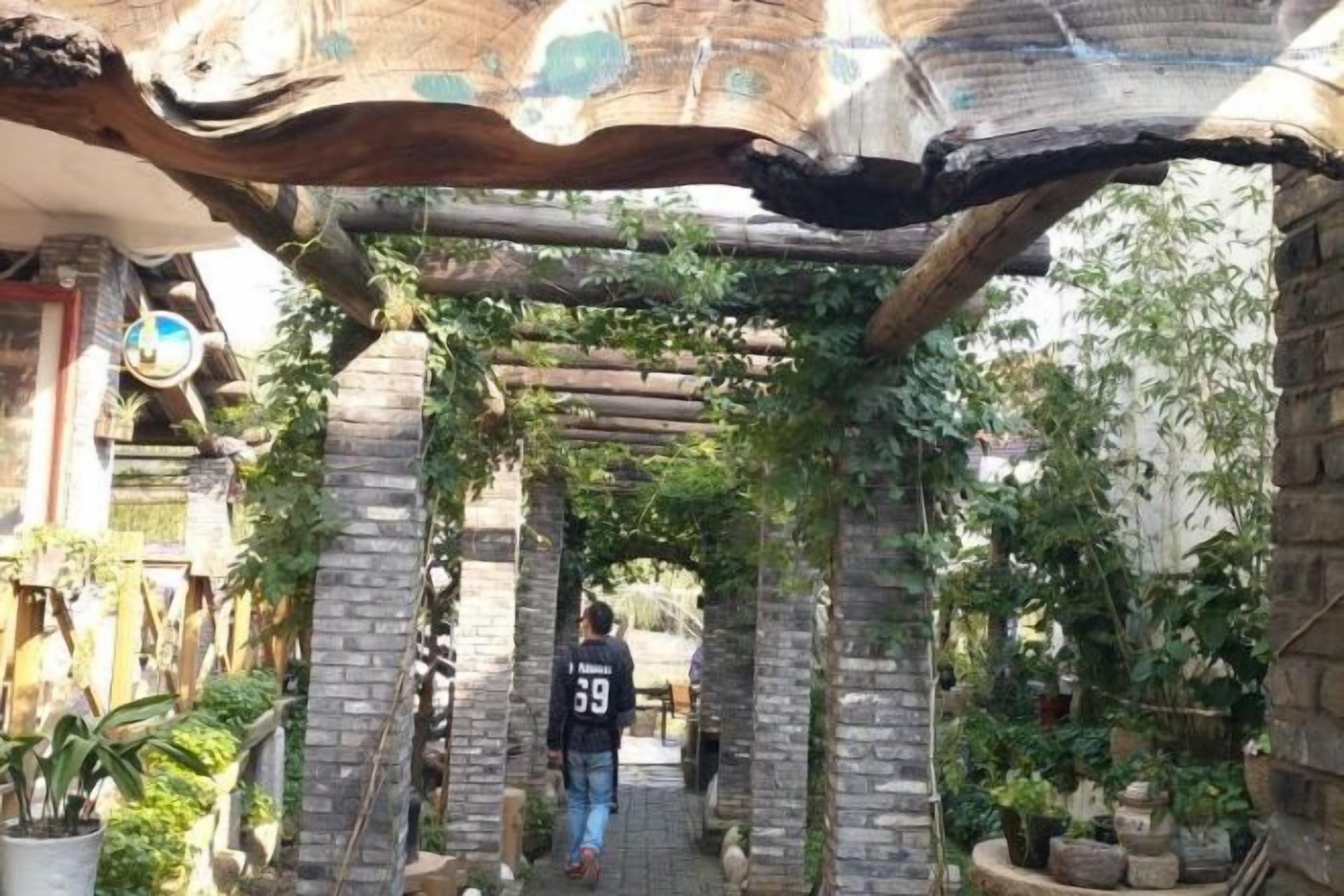 A stone archway with greenery, leading to a building entrance.