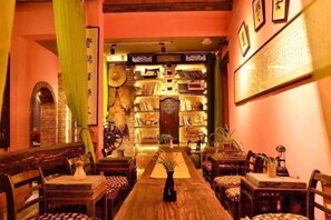 A traditional interior with a long wooden table, chairs, and a bookshelf filled with books. - Banduo Youlian Hostel (Shanghai)