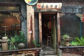 A traditional Chinese building with a wooden entrance, potted plants, and a sign with Chinese characters. - Banduo Youlian Hostel (Shanghai)