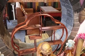A circular wooden chair with a cushioned seat and backrest, a small table, and a decorative item with a candle holder. - Banduo Youlian Hostel (Shanghai)