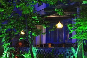 A building with a brick wall, a hanging light fixture, and a balcony with chairs. - Banduo Youlian Hostel (Shanghai)