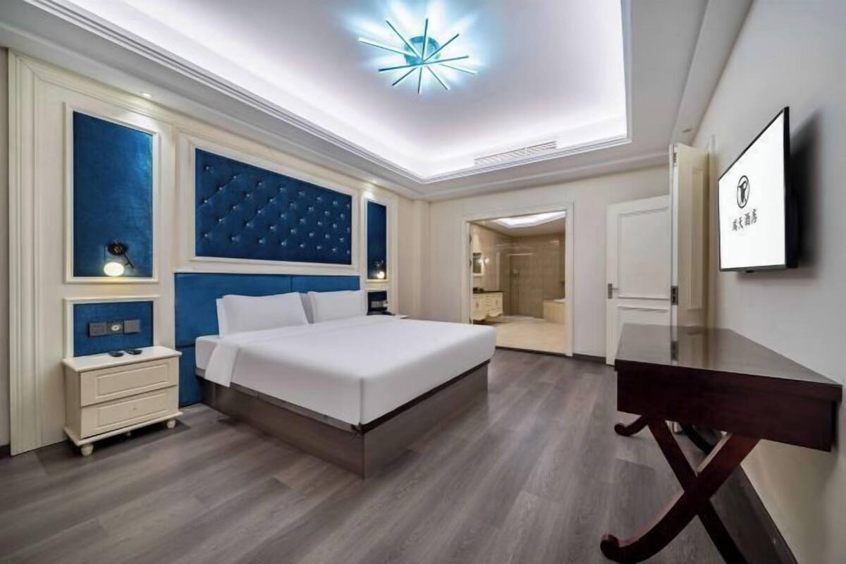 A modern hotel room with a large bed, a desk, and a television.